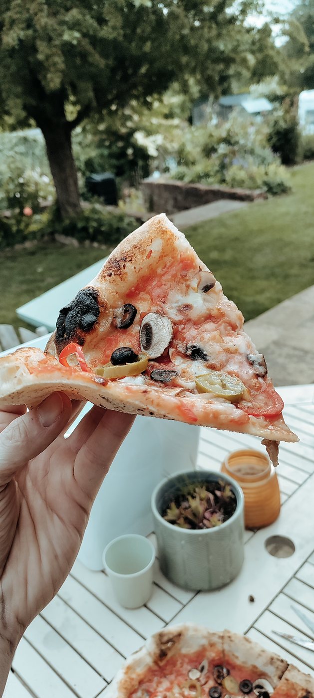 Slice of Neapolitan-style pizza showing soft crust and melted cheese